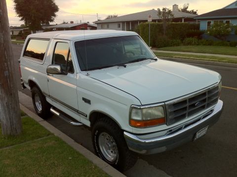 1992 Ford Bronco - White 1992 Ford Bronco parked on a residential street during sunset.