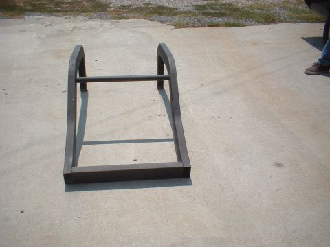 1969 Ford Torino - A metal frame part sits on a concrete driveway with a person's legs visible on the right.