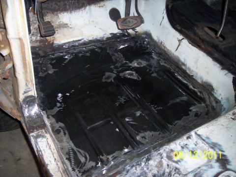 1973 Ford F-250 - The interior floor of a vehicle shows extensive rust repair and undercoating.