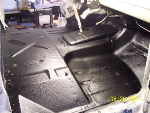 1973 Ford F-250 - The interior floor of a vehicle shows a fresh coat of black protective coating.