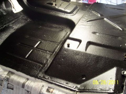 1973 Ford F-250 - Close-up of a black painted truck floor pan, showing its textured surface and mounting points.