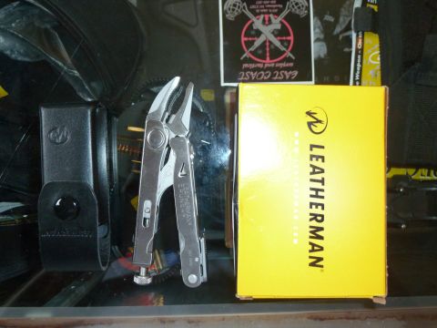 1992 Ford Mustang - Open Leatherman multi-tool pliers standing beside its yellow retail box and a sheath on a shelf.