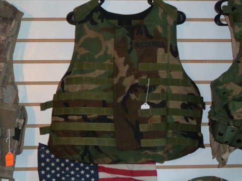 1992 Ford Mustang - Multiple pieces of tactical gear, including a camouflage vest with a name patch, are displayed on a wall.