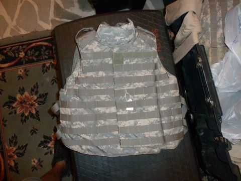 1992 Ford Mustang - A piece of digital camouflage body armor is displayed, MOLLE webbing and a small white tag attached.