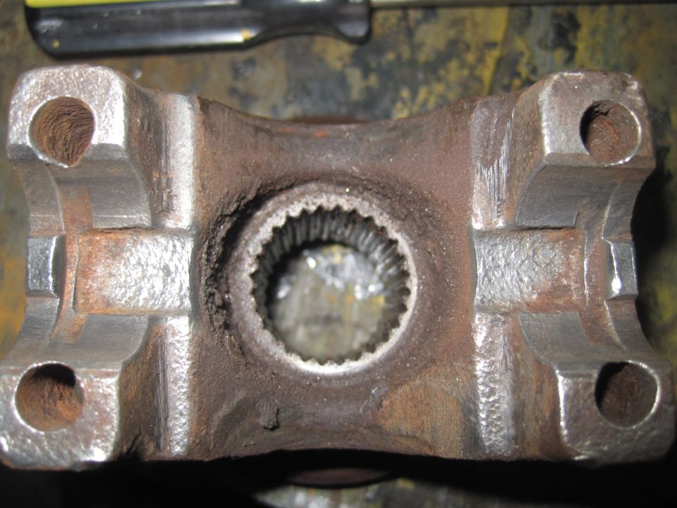 Rusty driveshaft U-joint yoke with splined opening and four bolt holes