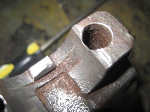 1979 Ford Bronco - A close-up view of a rusty metal suspension part, showing wear and a circular opening.