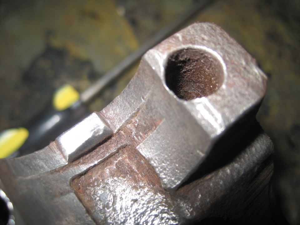 Close-up of a rusty metal suspension component with a circular hole