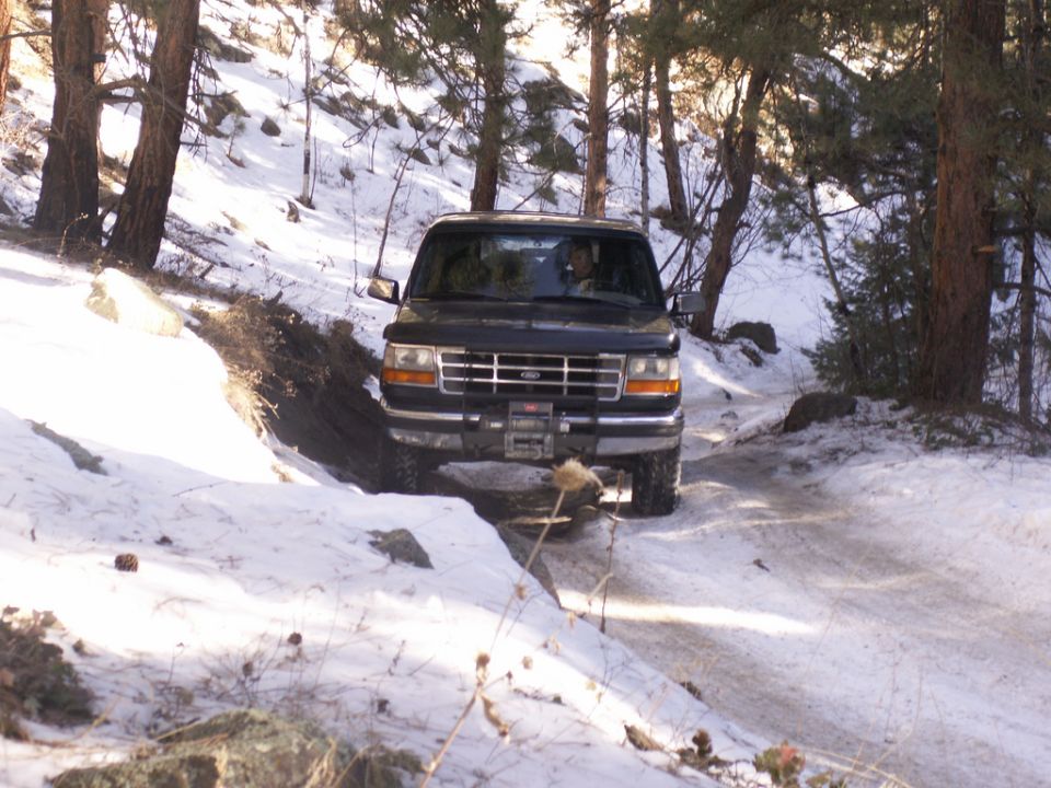 Black 1995 Ford Bronco driving on snowy road