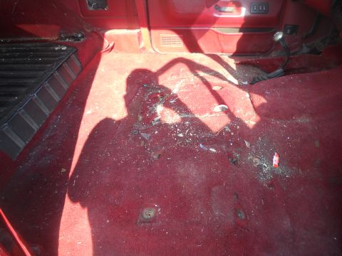1991 Ford Bronco - The interior of a 1991 Ford Bronco shows red carpeting and the shadow of the photographer.
