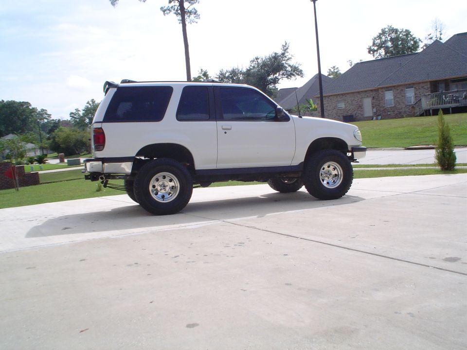 White lifted two-door Ford Explorer SUV in side profile on a driveway.