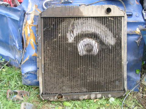 1979 Ford Bronco - A damaged blue vehicle body is visible behind a radiator, suggesting a collision or significant wear.