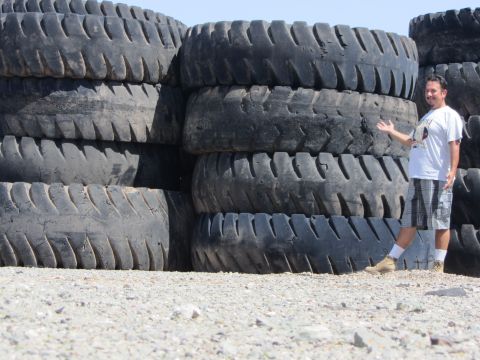 1987 Suzuki Samurai - A man stands next to a large stack of tires, possibly for sale or disposal.