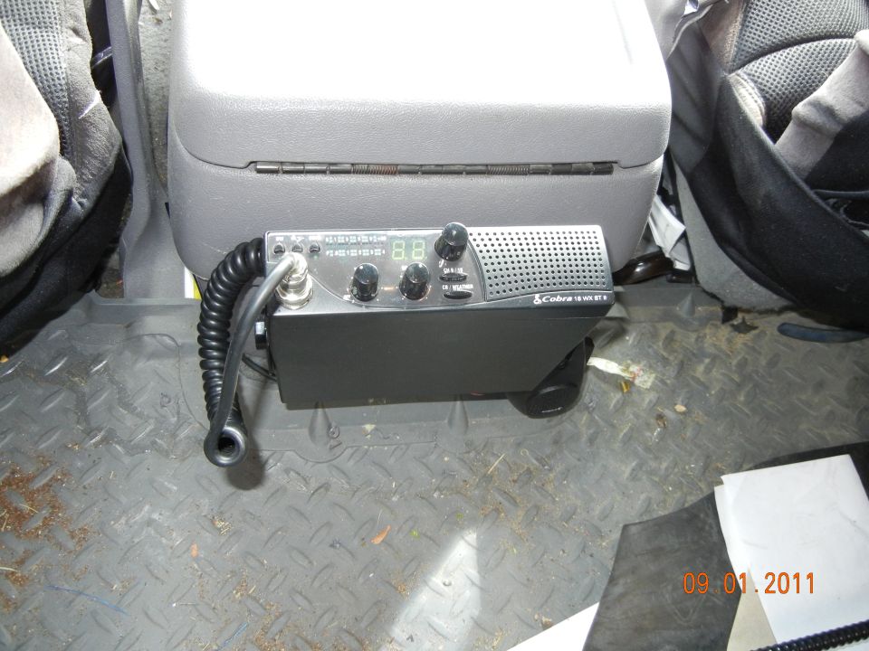 Cobra CB radio with digital display and microphone, mounted between vehicle seats