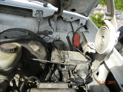 1996 Ford Bronco - Close-up view of engine bay components in a white vehicle, showing various hoses and electrical connections.
