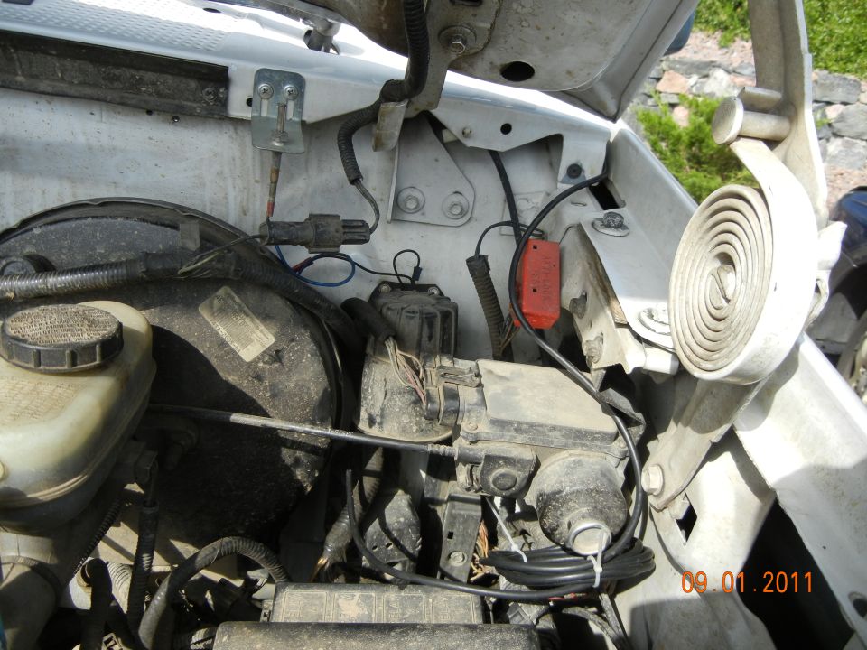 White vehicle engine bay with brake booster, master cylinder, and wiring harness visible