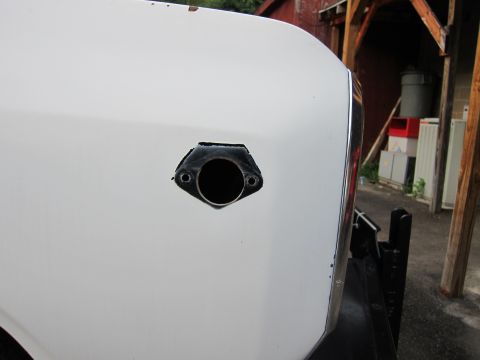 1987 Dodge 1500 - Close-up of a white truck fender showing a circular opening, possibly for a marker light, with a black gasket.