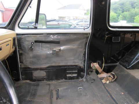 1987 Dodge 1500 - The interior of a truck cab is shown with the door panel removed and the floor exposed, indicating disassembly.
