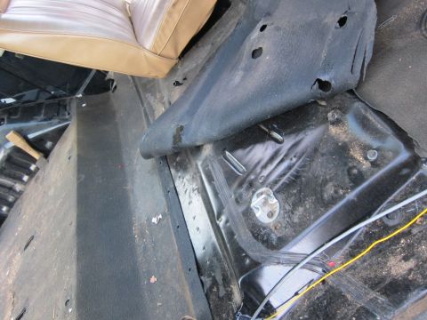 1987 Dodge 1500 - The interior floor of a vehicle is visible, with exposed metal and a portion of the passenger seat.