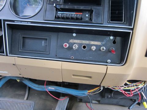 1987 Dodge 1500 - A close-up view of a vehicle's dashboard, showing a panel with several custom-installed switches and exposed wiring beneath.