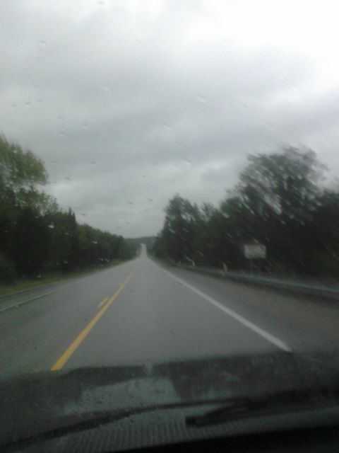 1988 Ford Bronco - The road ahead is wet and empty under a gloomy, overcast sky.
