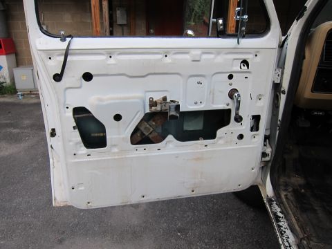 1987 Dodge 1500 - The interior of a vehicle door is shown with its internal components exposed, including the window regulator and door handle assembly.