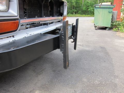 1987 Dodge 1500 - Front view of a truck's bumper, showing a custom license plate mount and worn paint.