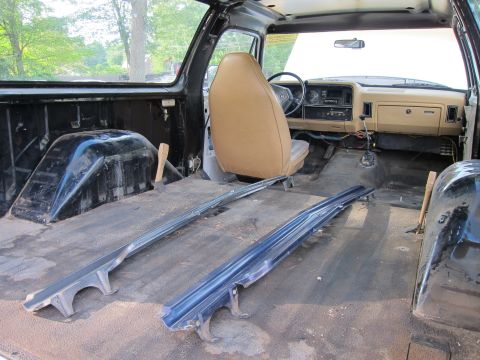 1987 Dodge 1500 - The interior of a pickup truck is shown with the seats removed, revealing the floor and dashboard area.