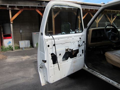 1987 Dodge 1500 - Interior view of a white truck with the driver's side door panel removed, revealing the inner workings.