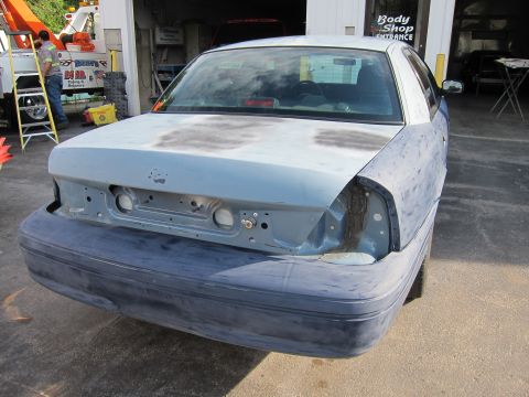 1987 Dodge 1500 - Car body in primer at a body shop, undergoing repairs.