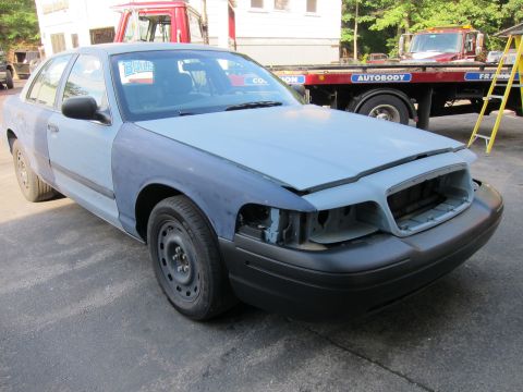 1987 Dodge 1500 - A car with mismatched body panels and missing headlights sits in front of a tow truck.