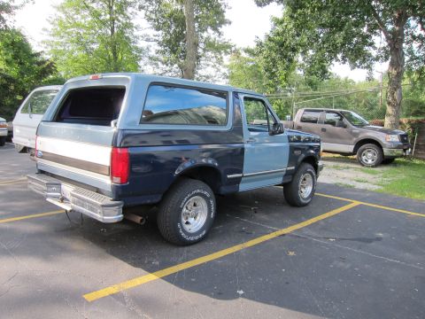 1987 Dodge 1500 - This Ford Bronco is parked next to another pickup truck in a parking lot.