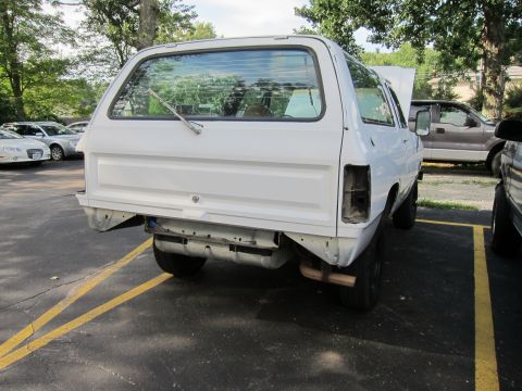 1987 Dodge 1500 - This white pickup truck is missing its rear bumper and taillight, with its hood open.