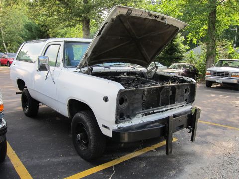 1987 Dodge 1500 - A white SUV, likely from the 1980s, is parked with its hood open, revealing a disassembled front end.