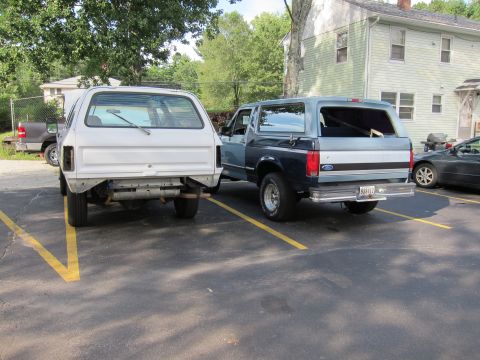 1987 Dodge 1500 - Two SUVs parked in a lot, one appears to be undergoing repairs.