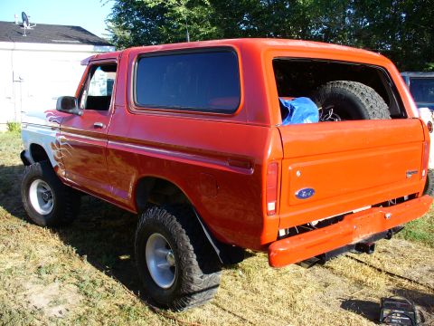 1979 Ford Bronco - This lifted Ford Bronco has flame decals on its front fender and a spare tire visible in the cargo area.