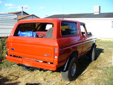 1979 Ford Bronco - This 1979 Ford Bronco is seen from the rear, with a spare tire and blue tarp visible inside the cargo area.
