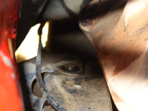 1979 Ford Bronco - Underside view of vehicle components, including an exhaust pipe and frame, with visible rust and a red panel.