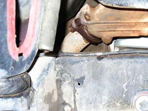 1979 Ford Bronco - Close-up view of a rusty exhaust manifold and pipe connection on a vehicle.