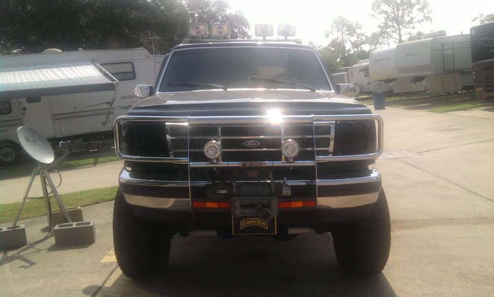 Black Ford truck front view with chrome grille, winch, and roof-mounted lights