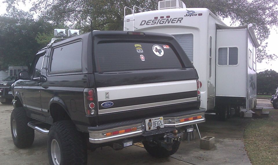 Lifted black Ford Bronco parked next to a white Jayco RV, rear view. License plate reads BFV2L