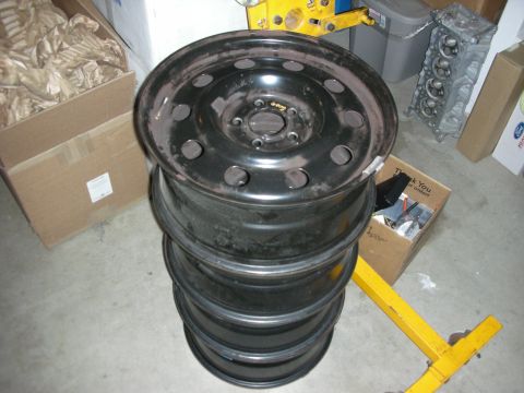 2004 Ford Crown Victoria - A stack of four black steel wheels is shown in a garage setting.