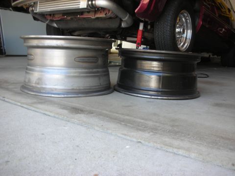 2004 Ford Crown Victoria - Comparison of two wheels, one raw metal and one black, with a vehicle's underside and a chrome wheel visible.