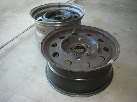 2004 Ford Crown Victoria - Two steel wheels are shown on a concrete surface, one appears to be rusty.