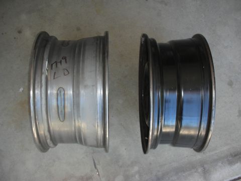 2004 Ford Crown Victoria - Two car wheels are shown, one in silver and the other painted black. The silver wheel has handwritten markings on its side.
