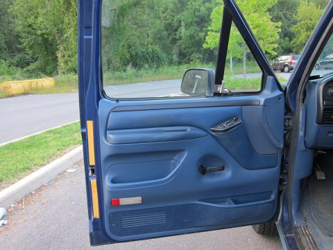 2001 Ford Crown Victoria - Interior view of a blue door panel, showing the side mirror and door handle. The exterior is visible through the open door.