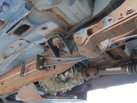 2001 Ford Crown Victoria - The underbody of a vehicle displays extensive rust and corrosion on its structural and mechanical components.