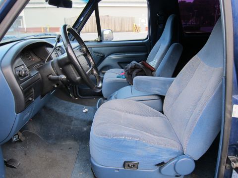2001 Ford Crown Victoria - The interior of a blue truck shows the driver's side and passenger seats, dashboard, and steering wheel.