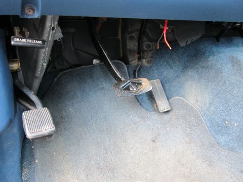 2001 Ford Crown Victoria - The interior footwell shows the brake release lever and the accelerator and brake pedals.