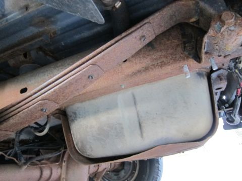 2001 Ford Crown Victoria - The undercarriage of a vehicle displays a fuel tank and heavily rusted suspension components.