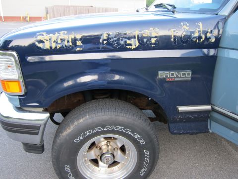 2001 Ford Crown Victoria - A blue Ford Bronco XLT shows significant paint damage on the fender, with partial text visible.